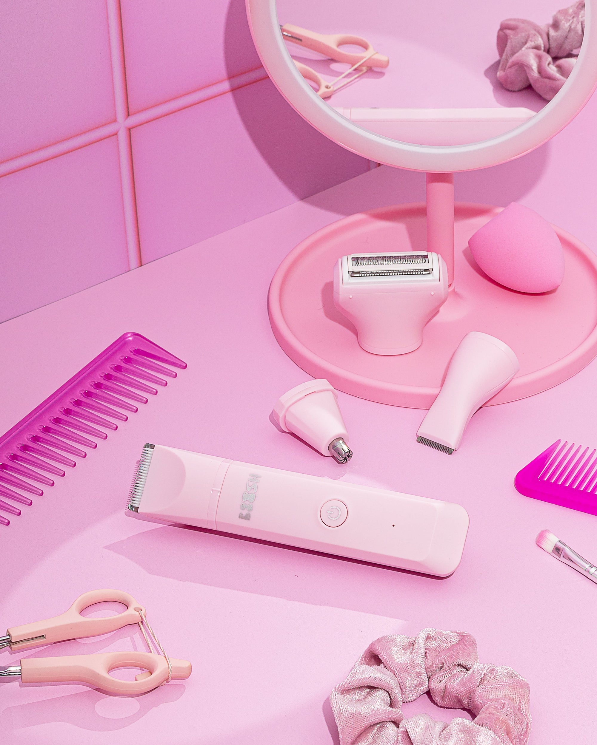 A collection of pink beauty accessories and the pink boosh trimmer coupled with grooming accessories arranged on a pink surface.
